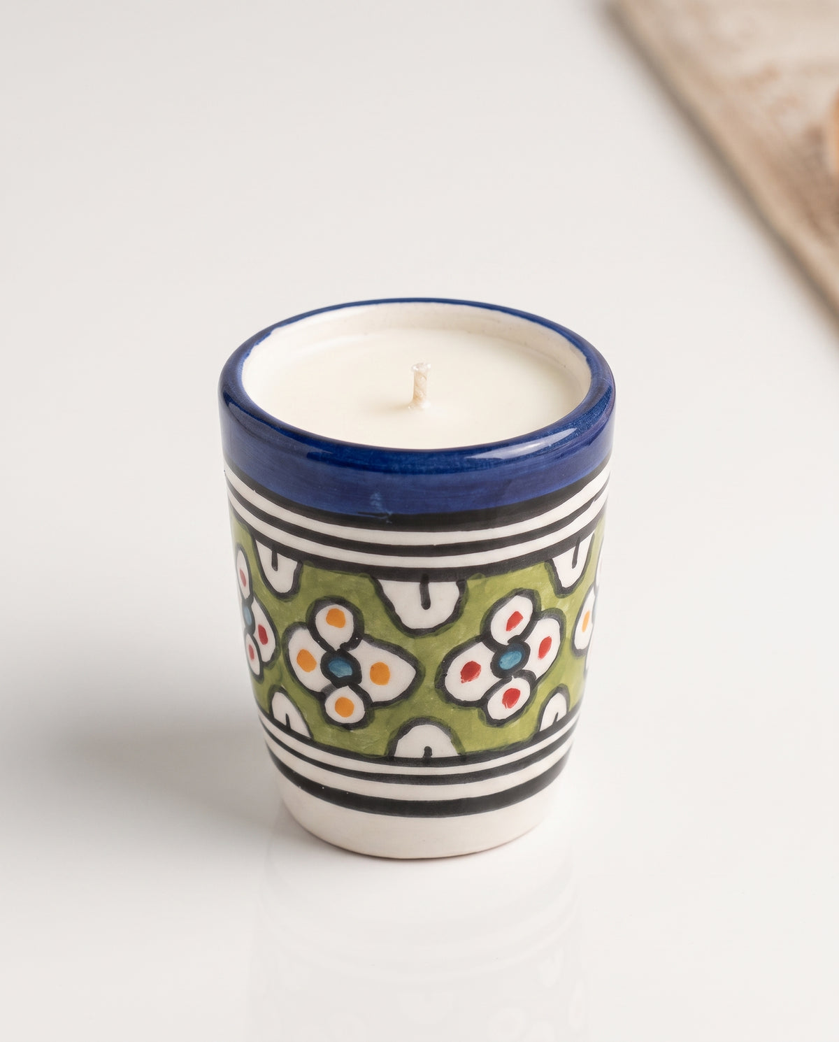 Bougie Ghita, petit format en terre cuite peint main (médaillons floraux blancs sur fond vert, points rouge/orange/bleu, rebord bleu) sur fond neutre, collection Fès My Candles Vibes